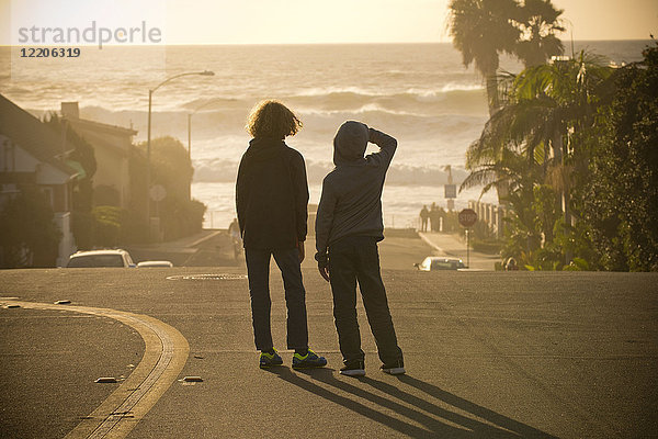 Jungen stehen auf der Straße und bewundern die Meereswellen