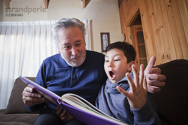 Hispanischer Großvater und aufgeregter Enkel beim Lesen eines Buches