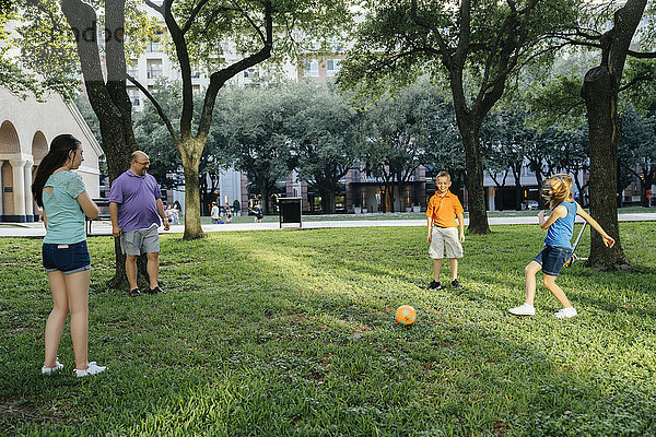 Kaukasische Familie kickt Fußball im Park