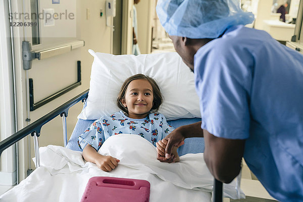 Arzt hält Hand eines Mädchens im Krankenhausbett