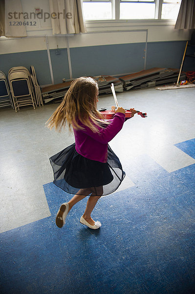 Kaukasisches Mädchen übt Geige und tanzt