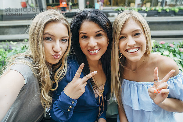 Lächelnde Frauen posieren und gestikulieren für ein Handy-Selfie