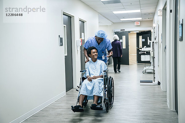 Krankenschwester schiebt Junge im Rollstuhl