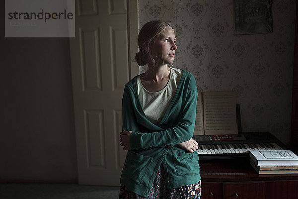 Porträt einer nachdenklichen kaukasischen Frau  die sich an ein Klavier lehnt