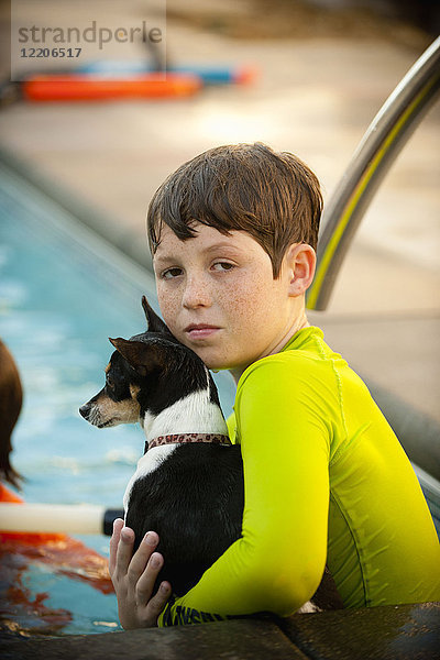 Kaukasischer Junge im Schwimmbad mit Hund