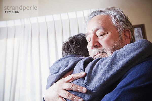 Hispanischer Großvater  der seinen Enkel umarmt