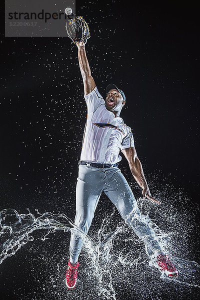 Wasser spritzt auf Beine Schwarzer Baseballspieler fängt Baseball