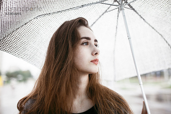 Kaukasische Frau hält weißen Regenschirm