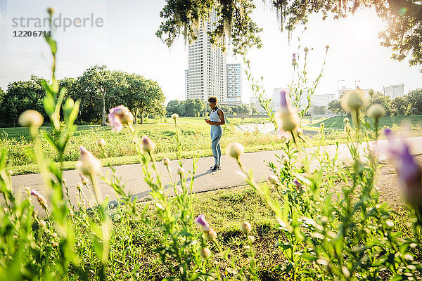 Mixed-Race-Frau steht auf Laufstrecke im Park hinter Wildblumen