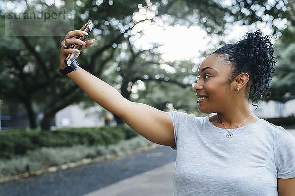 Lächelnde schwarze Frau  die für ein Handy-Selfie posiert