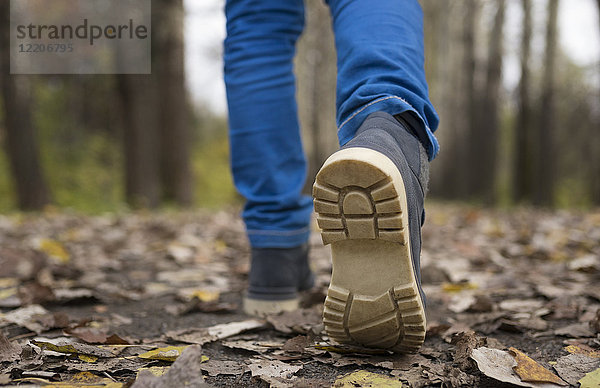 Sole of shoe of Caucasian boy walking on autumn leaves