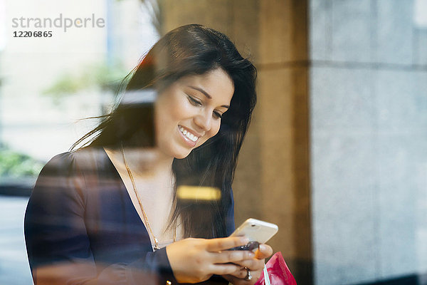 Smiling Hispanic woman texting on cell phone