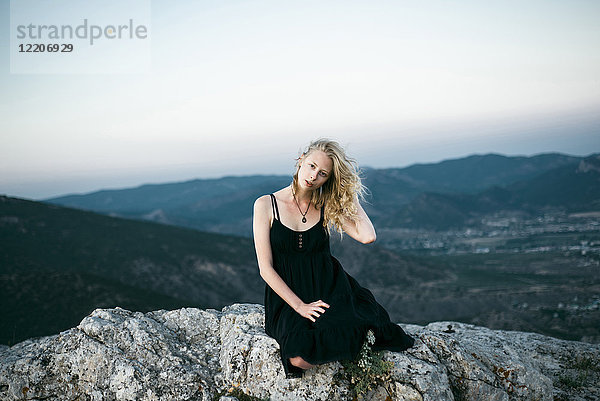 Caucasian woman sitting on rock near mountains