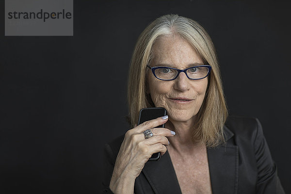 Portrait of smiling older Caucasian businesswoman holding cell phone