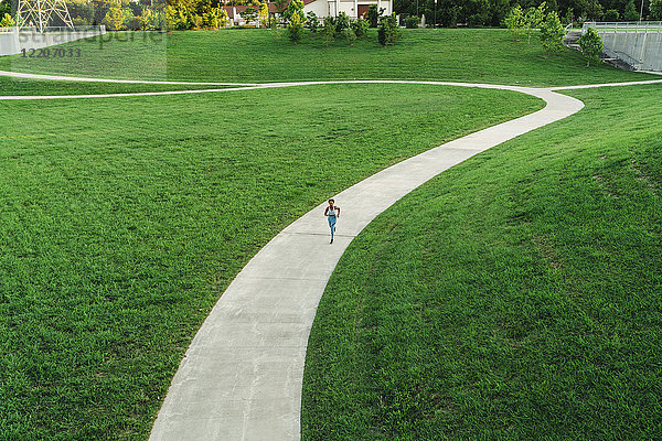 Distant mixed race woman running on winding path in park