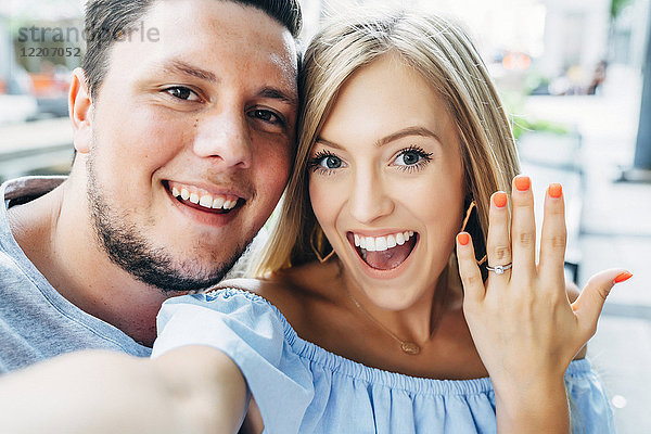 Lächelndes kaukasisches Paar posiert für Selfie mit Verlobungsring