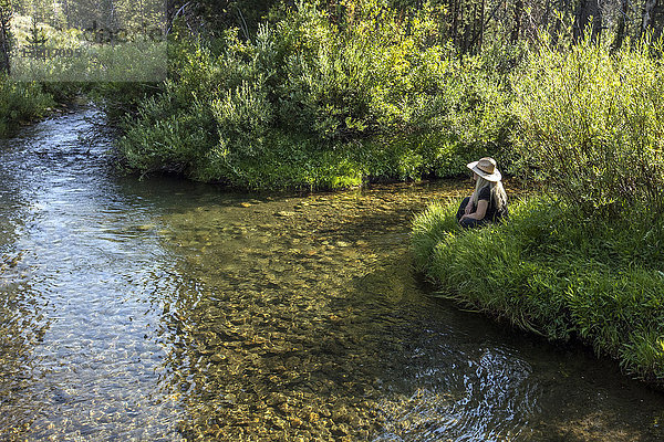 Caucasian woman sitting near tranquil river