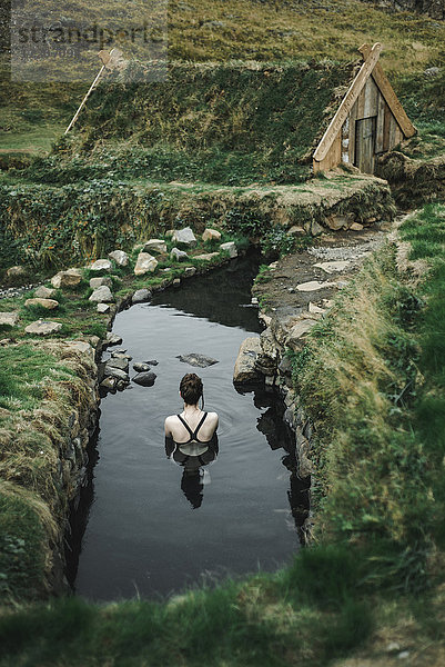 Caucasian woman swimming in pond near rural house
