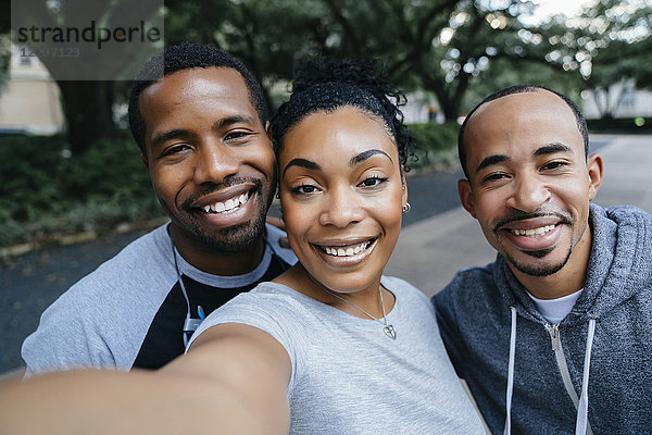 Smiling Black friends posing for cell phone selfie