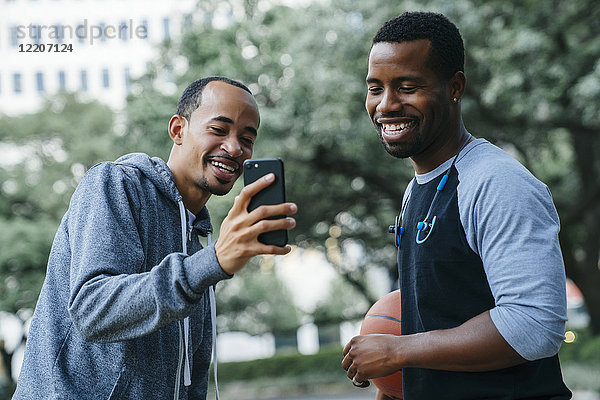 Smiling Black men texting on cell phone
