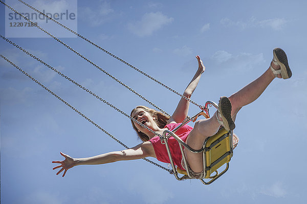 Smiling Caucasian woman riding swing on amusement park ride