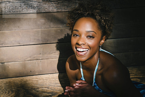 Portrait of smiling mixed race woman laughing near wooden wall