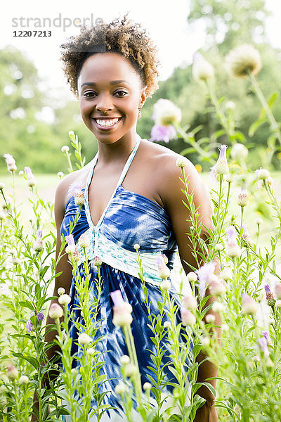 Portrait of smiling mixed race woman standing in wildflowers