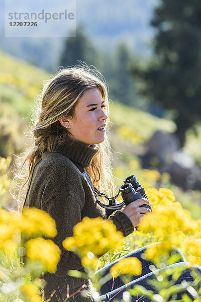 Caucasian girl in field holding binoculars