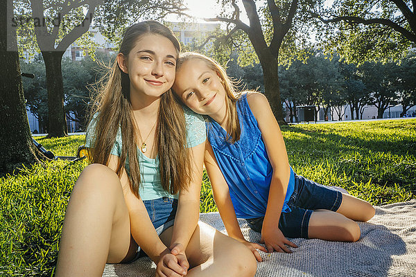 Portrait of smiling Caucasian girls on blanket in park