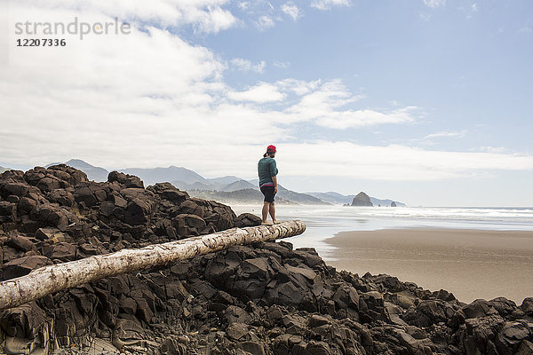Caucasian woman balancing on log on rocks at beach