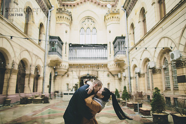 Caucasian couple kissing in courtyard