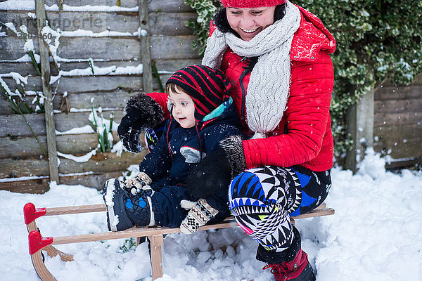 Mutter und Sohn im Schnee auf dem Schlitten