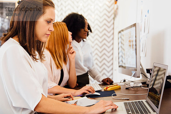 Kollegen im Büro benutzen gemeinsam einen Laptop