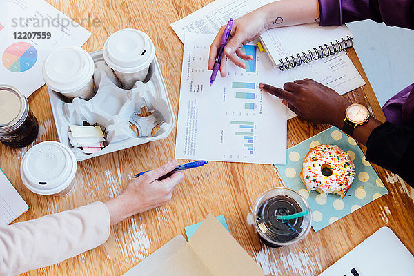 Draufsicht auf Doughnuts und Kaffee auf dem Schreibtisch