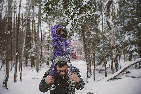 Vater und Tochter in verschneiter Landschaft  Vater trägt Tochter auf den Schultern