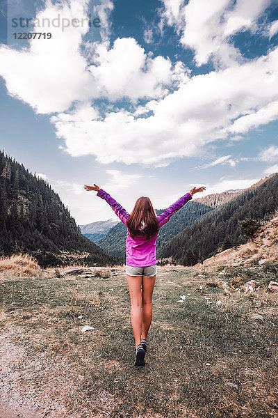 Junge Frau mit offenen Armen mit Blick über das Bergtal  Draja  Vaslui  Rumänien  Rückansicht