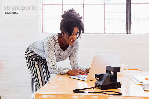 Frau in industriellem Bürogebäude mit Laptop