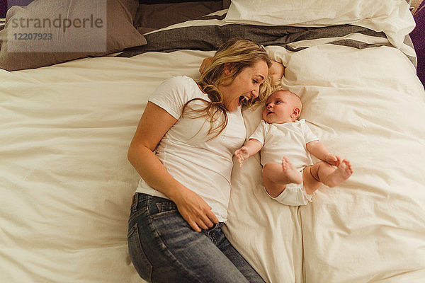 Draufsicht von Frau und Baby-Tochter im Bett liegend