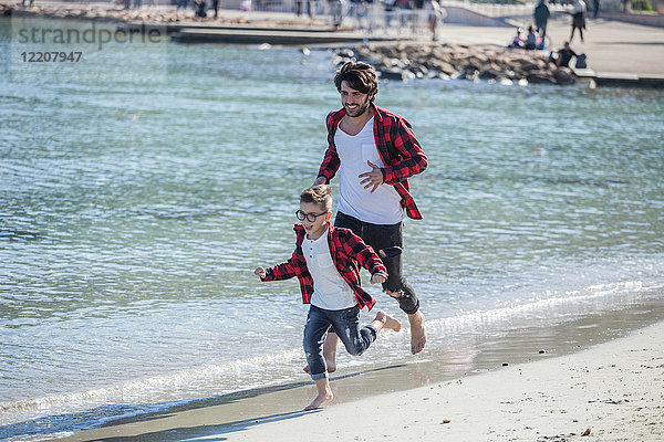 Vater und Sohn laufen am Strand entlang
