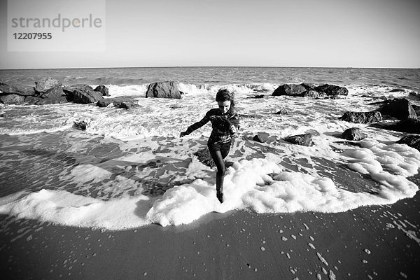 Frau rennt am Strand vor der Meereswelle davon  Oblast Odessa  Ukraine