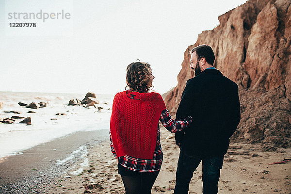Rückansicht eines romantischen Paares mittlerer Erwachsener  das am Strand spazieren geht  Oblast Odessa  Ukraine
