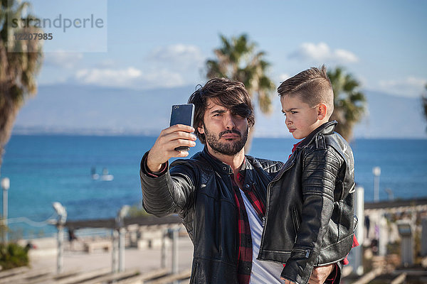 Vater und Sohn im Freien  Vater nimmt sich selbst mit Smartphone