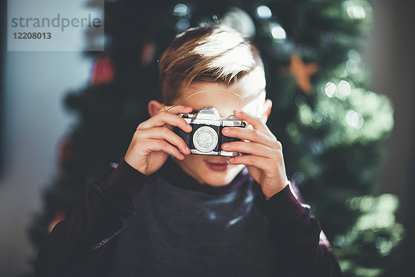 Junge beim Fotografieren  Weihnachtsbaum im Hintergrund