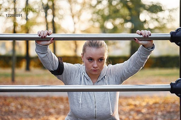 Kurvige junge Frau beim Training  lehnt sich im Park an Handlauf