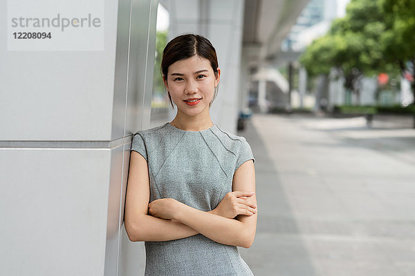 Porträt einer jungen Geschäftsfrau  die in einer Stadt an einer Wand lehnt  Shanghai  China