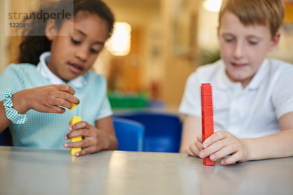 Schüler und Mädchen stapeln Spielzeugblöcke im Klassenzimmer der Grundschule