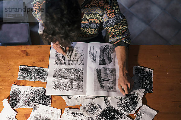 Draufsicht einer Zeichnung eines männlichen Künstlers im Skizzenbuch im Künstleratelier