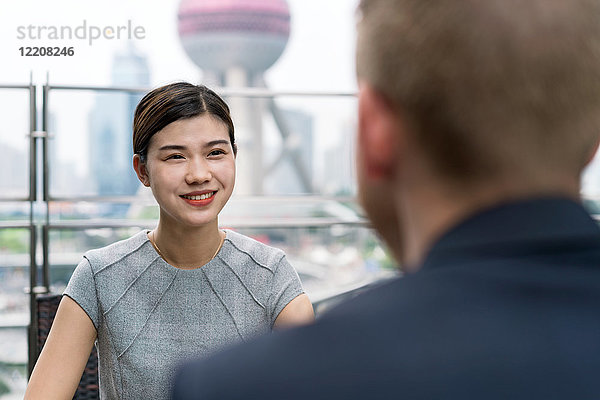 Über-die-Schulter-Ansicht einer jungen Geschäftsfrau und eines jungen Mannes bei einem Treffen im Strassencafé im Finanzzentrum von Shanghai  Shanghai  China