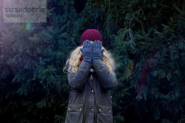 Frau bedeckt Gesicht  Tanne im Hintergrund