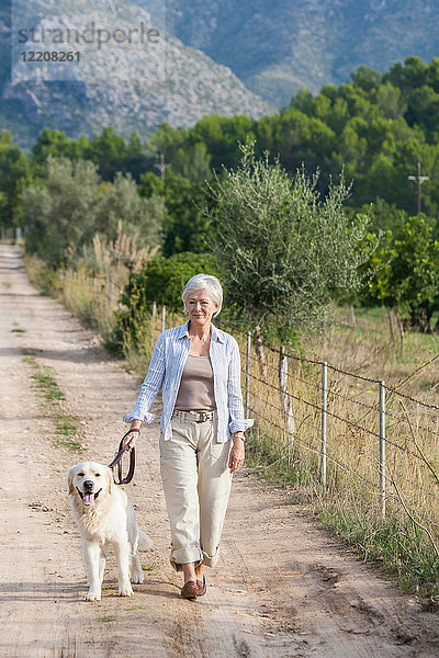 Porträt einer älteren Frau beim Spaziergang mit einem Hund